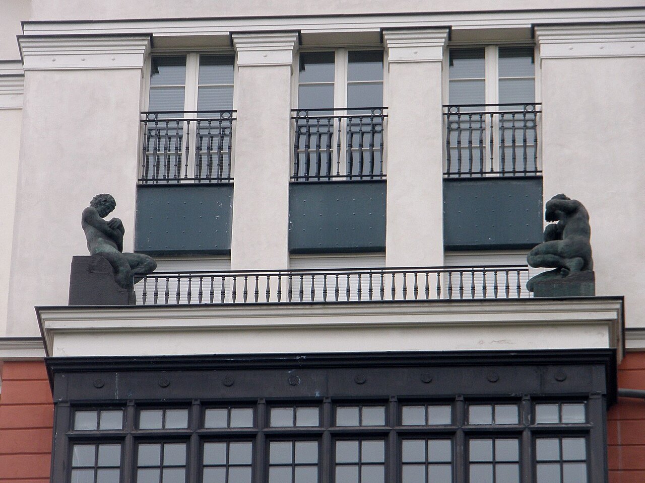 Seated bronze figures on a balcony ledge of the Artklass building