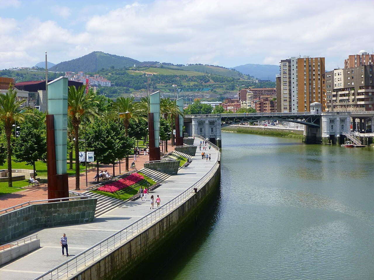 The riverside promenade at Abandoibarra curving downstream toward the Deusto bridge
