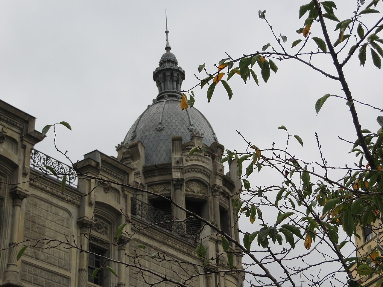 A corner dome of Azkuna Zentroa seen through autumn leaves