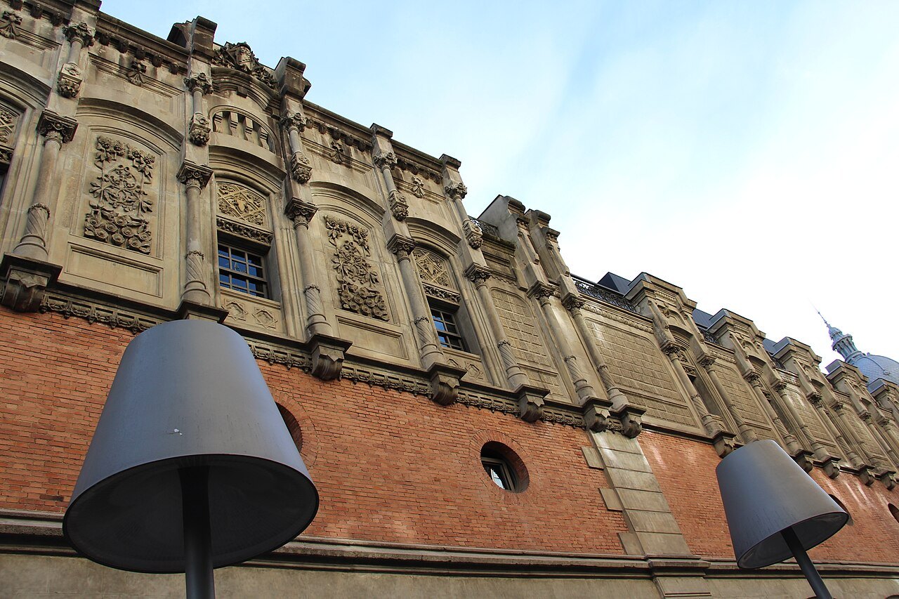 Brick and carved stone of the Azkuna Zentroa façade, with tall black street lamps