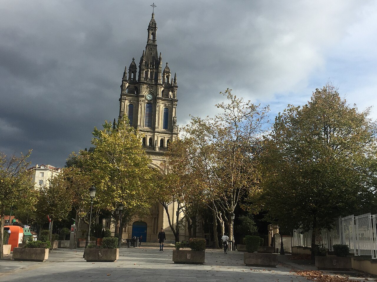 The tower of the Basilica of Begoña above the trees under a stormy sky