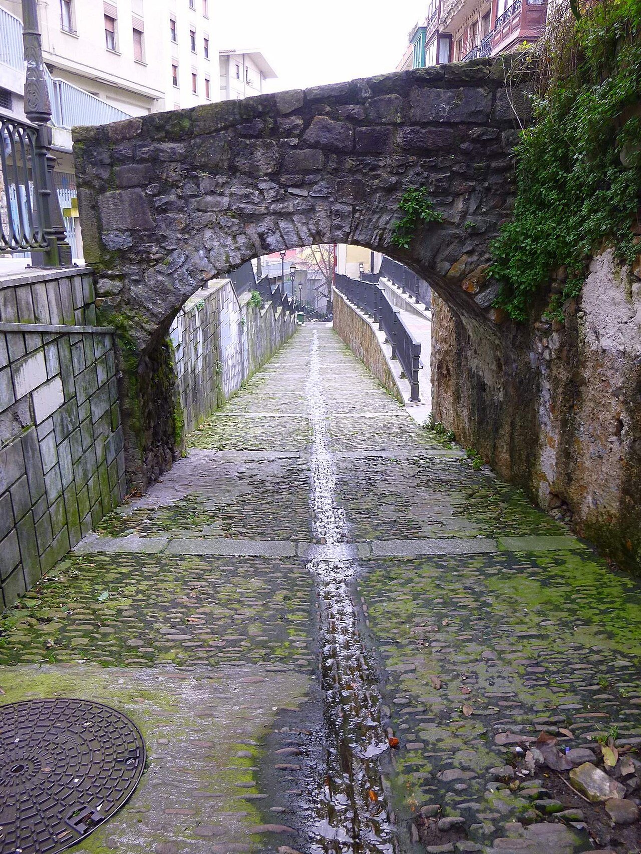 An old stone arch over the cobbled path of the Calzadas de Mallona
