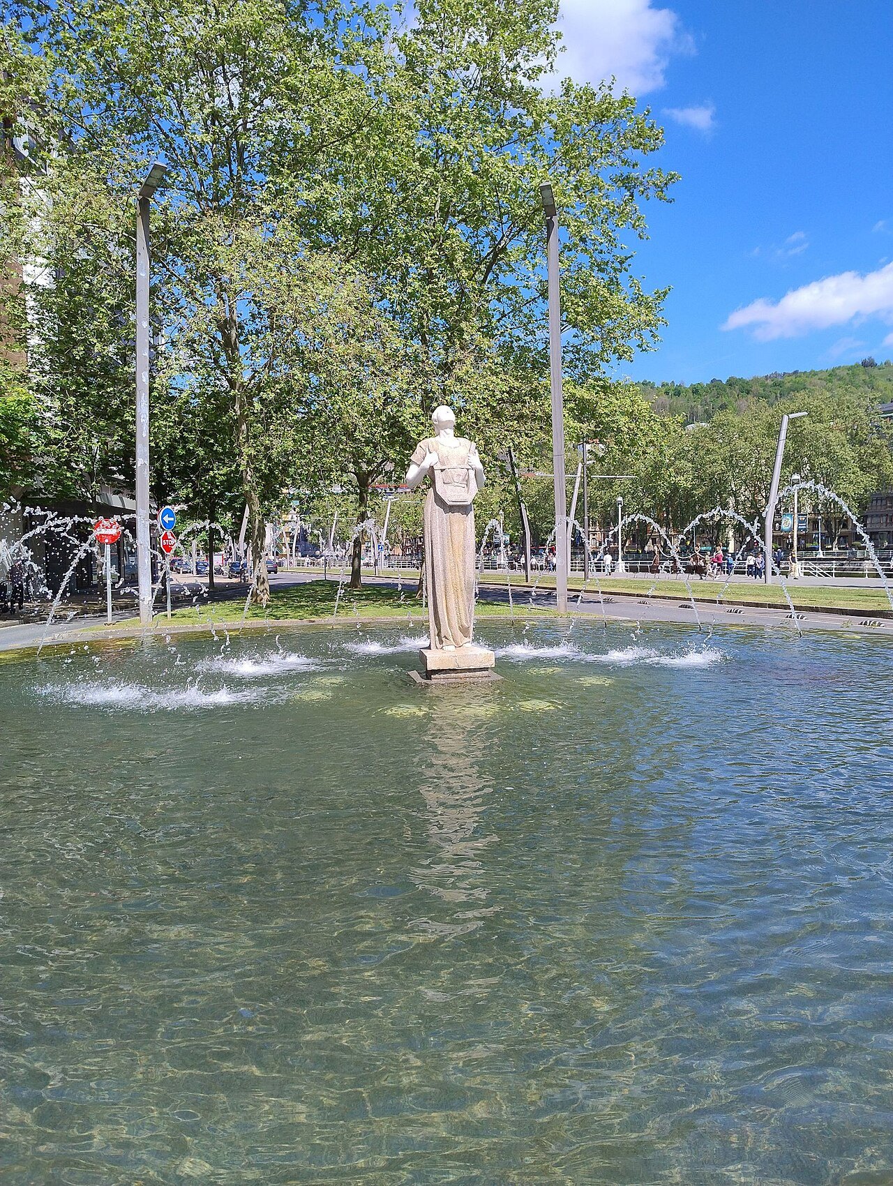 A statue standing in a fountain pool beside the riverside walk at Uribitarte