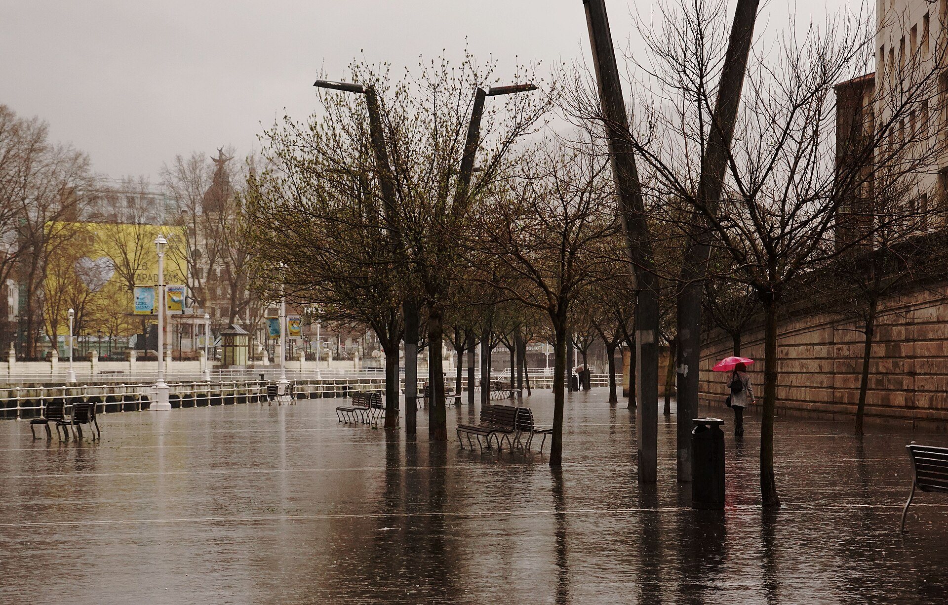 A red umbrella on the flooded quay of the Muelle de Ripa in the rain