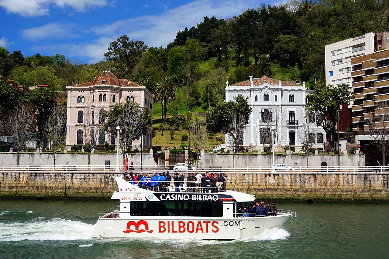 A sightseeing boat passing the old villas on the Deusto bank