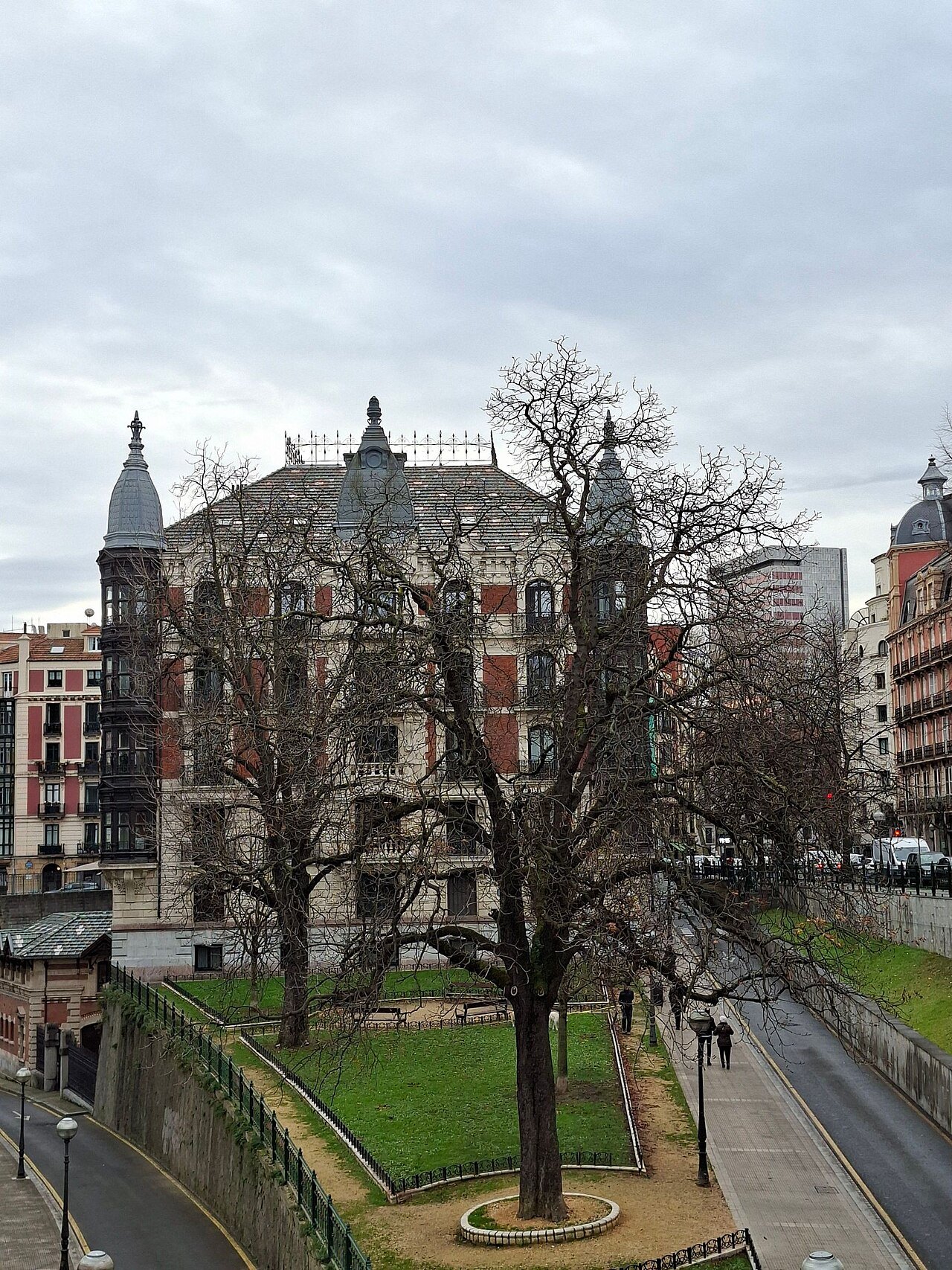 A garden square beside the river, an old stone building behind bare trees