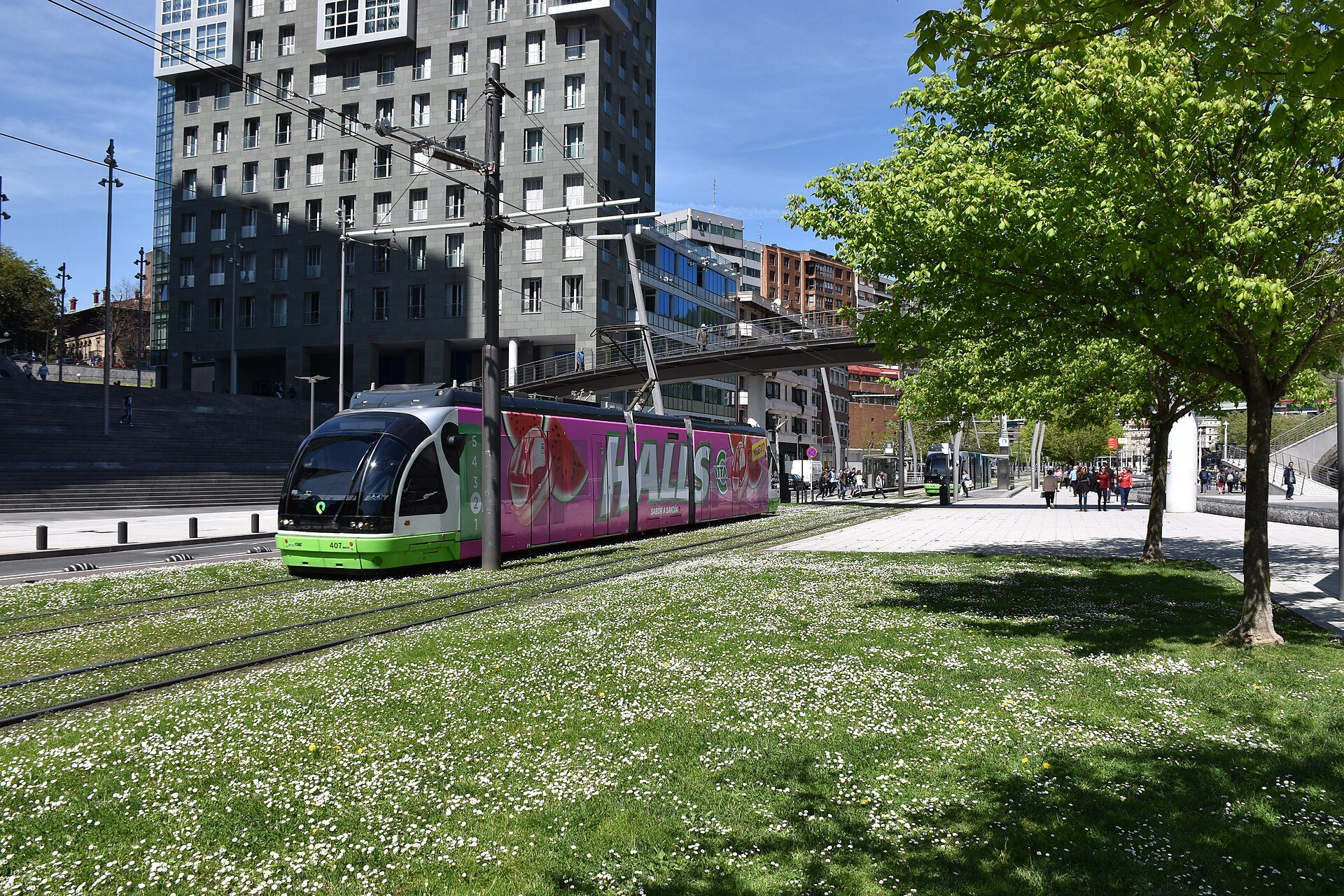 A tram crossing the grass at Uribitarte below the Isozaki towers