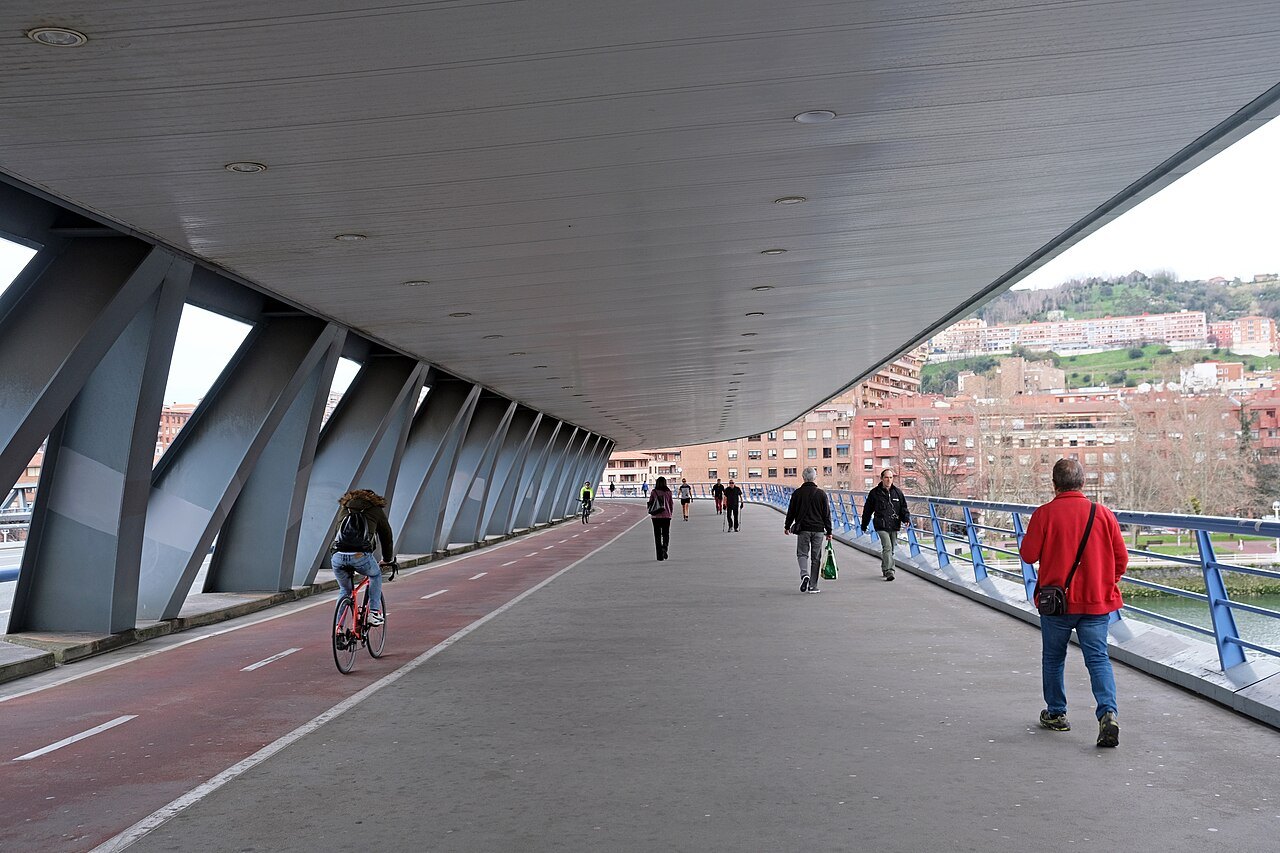 Walkers and a cyclist on the covered deck of the Euskalduna bridge