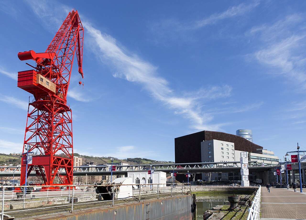 The red Carola crane over the quay, the dark block of the Euskalduna behind
