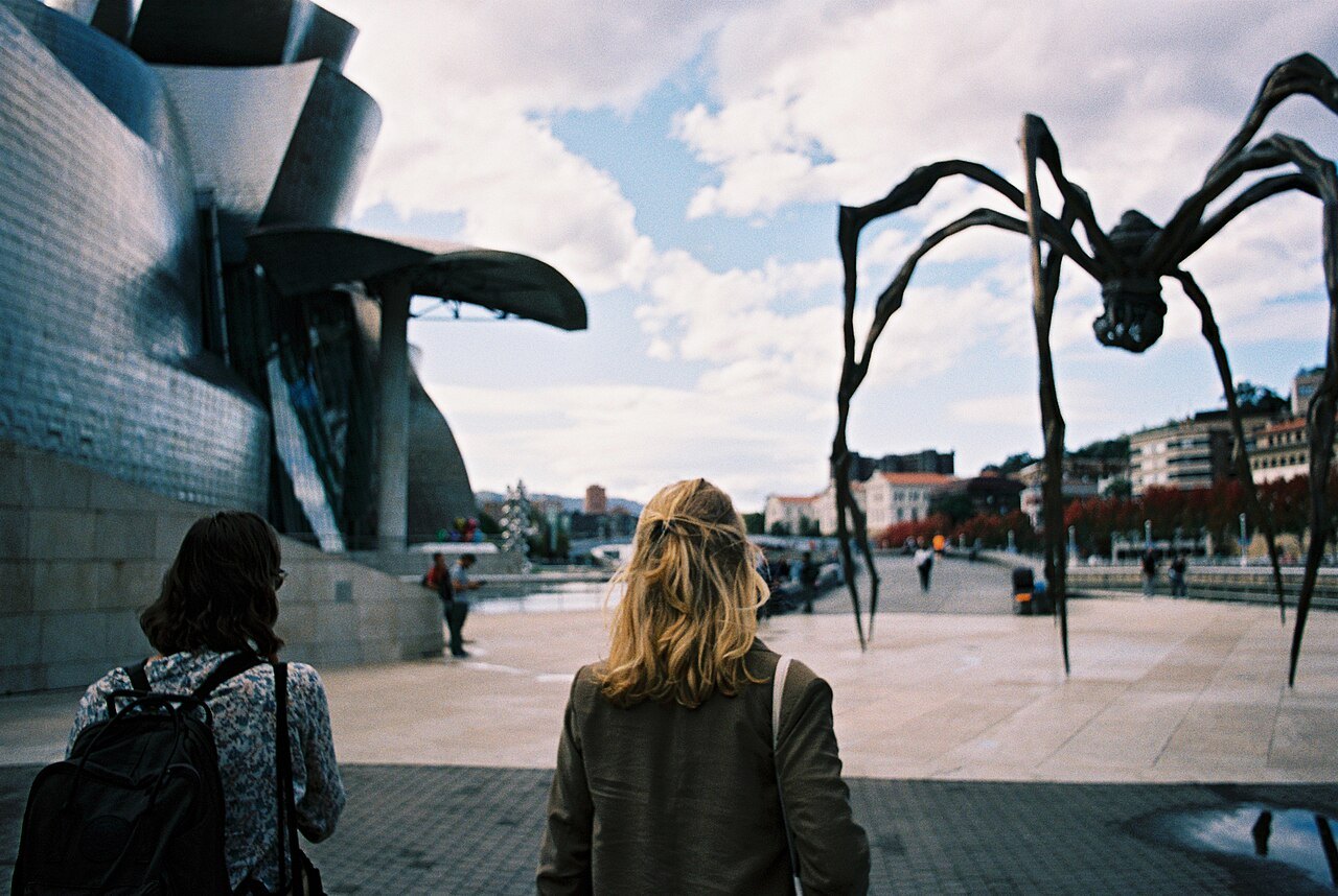 Two visitors walking toward Louise Bourgeois's spider Maman beside the museum