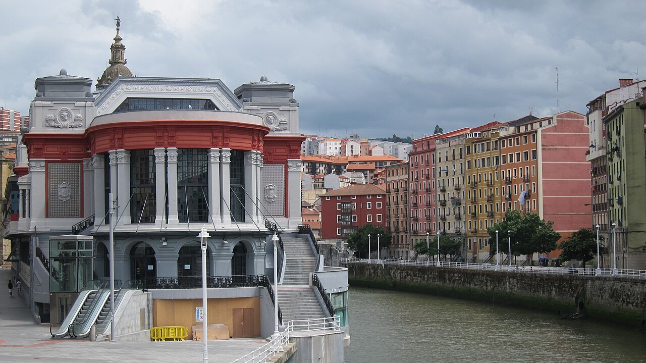 The Ribera market and the painted houses of the old town seen from the opposite bank