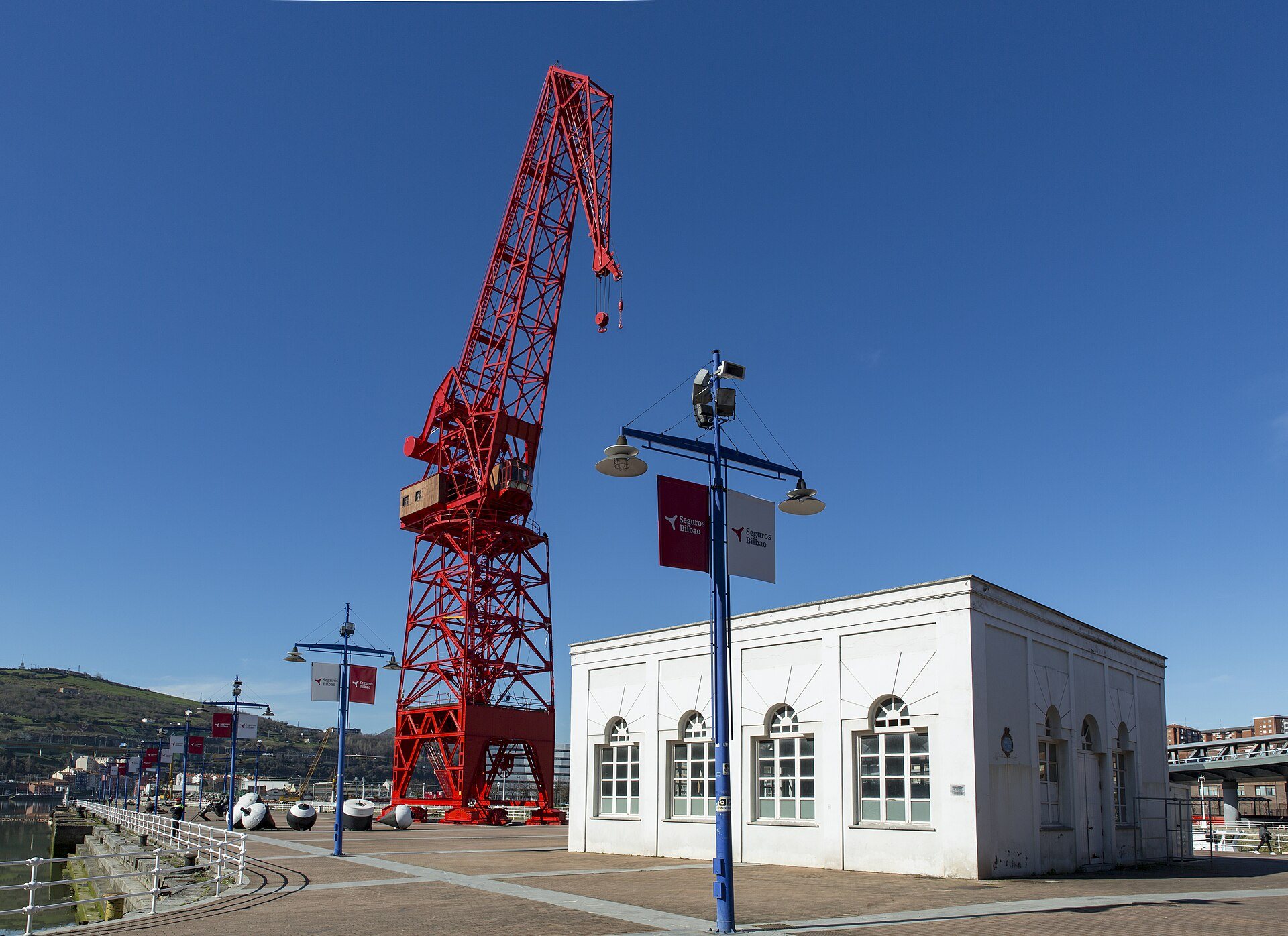 The red Carola crane and the white pump house on the quay of the Itsasmuseum