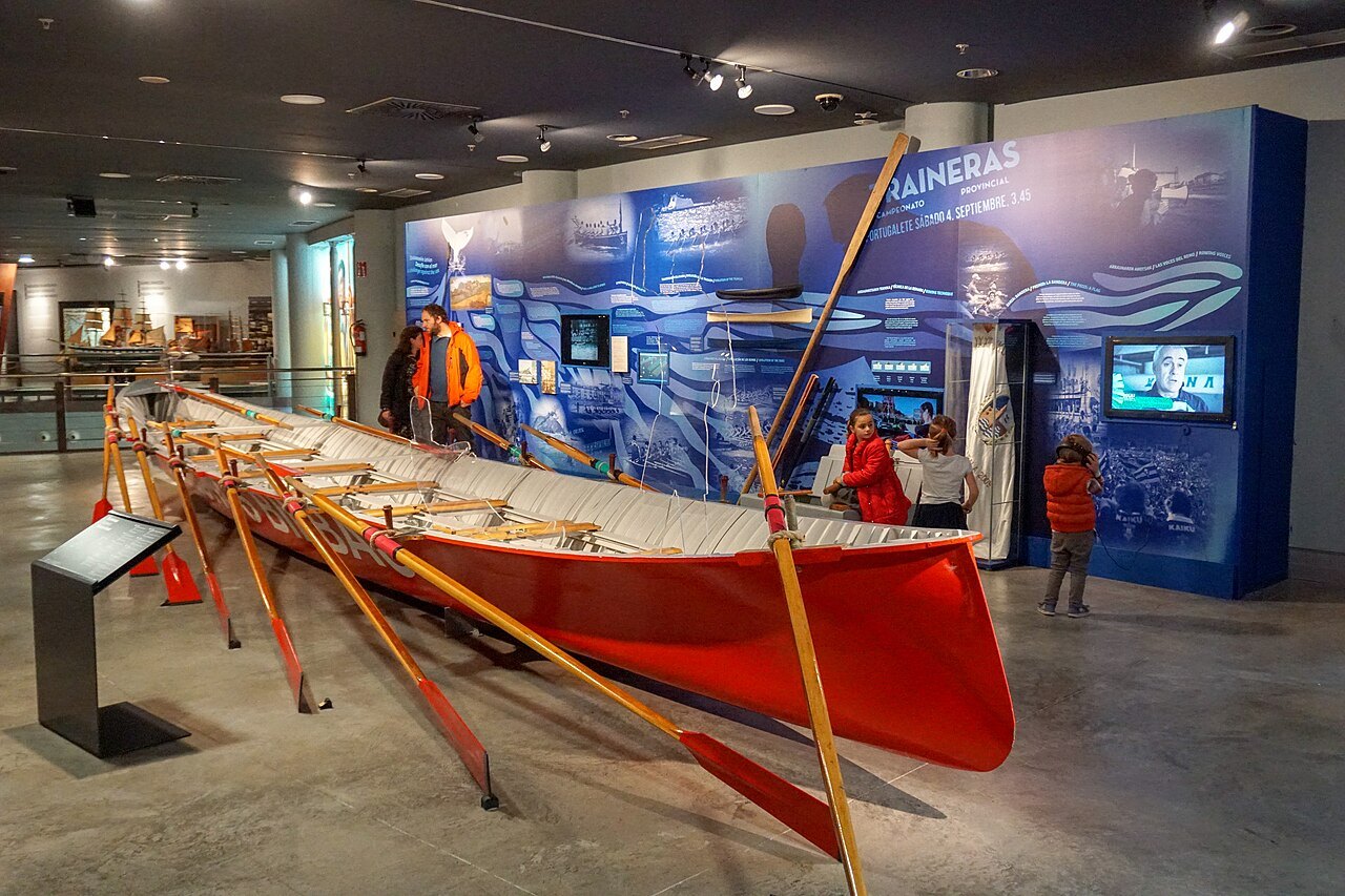 The rowing section of the Itsasmuseum, a red trainera and its oars