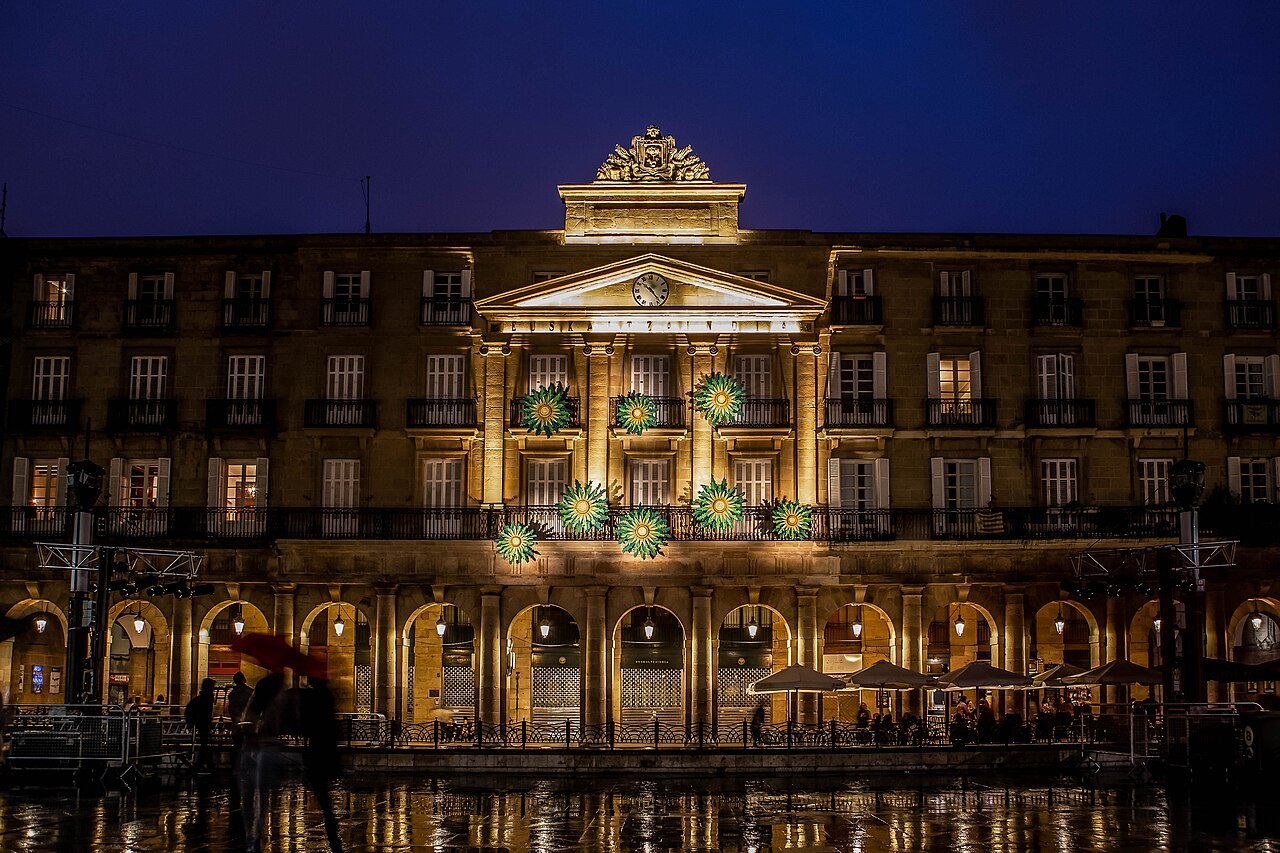 The Plaza Nueva lit at night, its central building decorated with lights