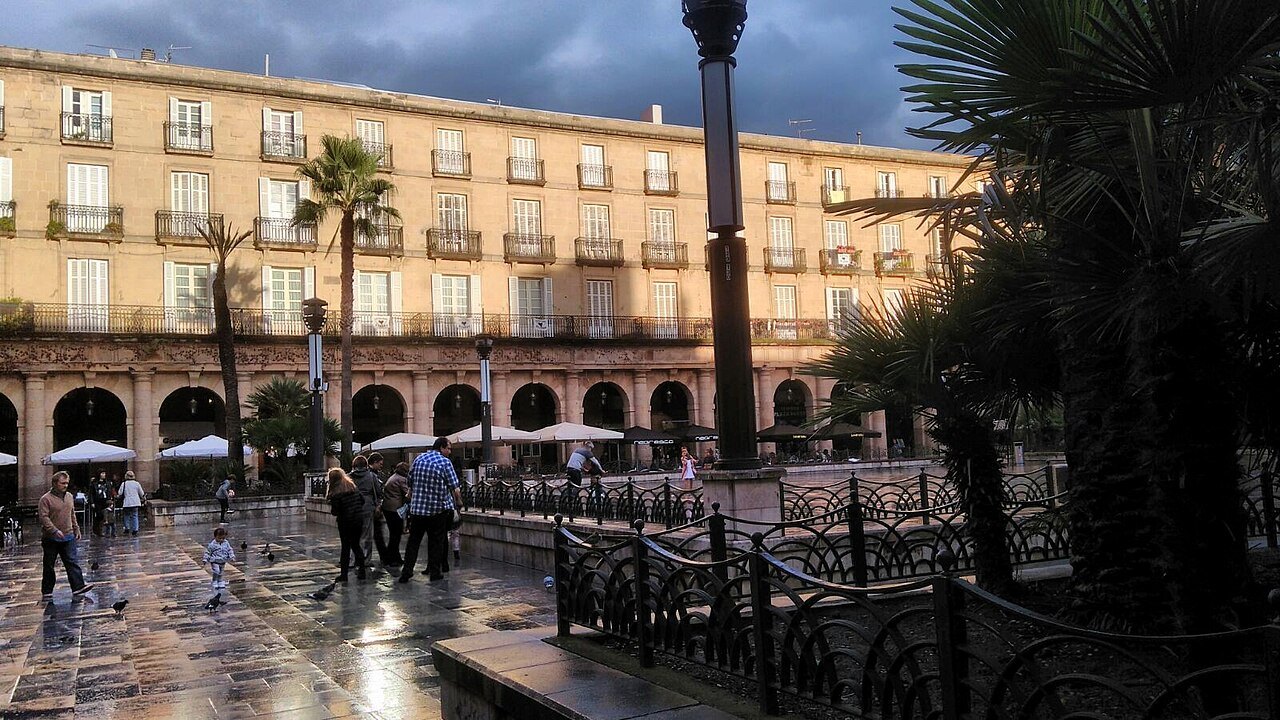 The Plaza Nueva on a wet evening, palms and street lamps in the square