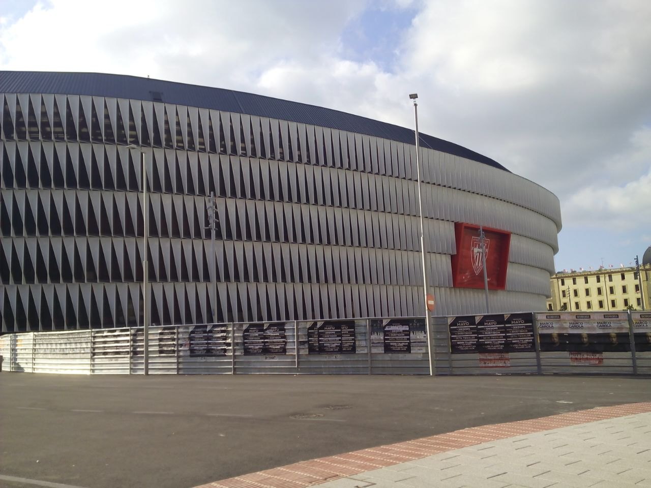 The stadium's ribbed white skin wrapping around its corner