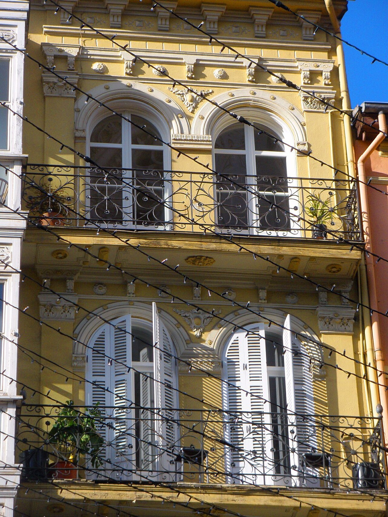 Arched windows and wrought-iron balconies on a yellow house by the cathedral
