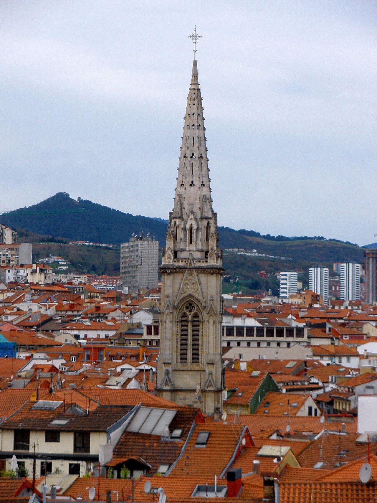 The cathedral spire rising above the old town roofs, hills behind
