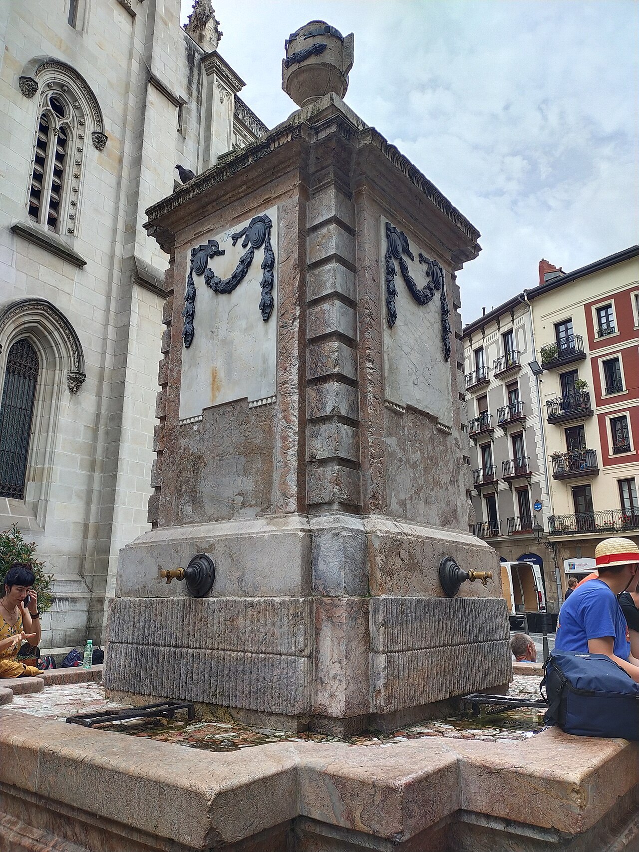 A stone fountain with garlands beside a church in the old town