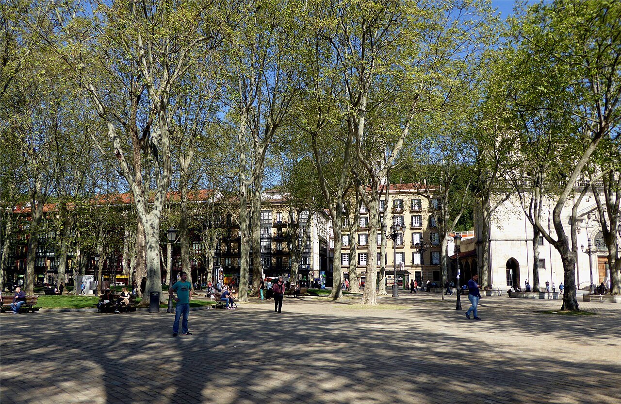 Strollers under the plane trees of the Arenal on a spring day